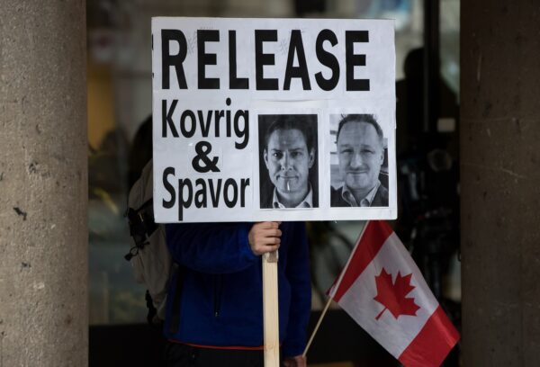Một thanh niên cầm một tấm biển có ảnh của hai ông Michael Kovrig và Michael Spavor, những người đã bị giam giữ ở Trung Quốc hơn một năm, bên ngoài Tòa án Tối cao British Columbia, nơi giám đốc tài chính Huawei Mạnh Vãn Châu đang tham dự một phiên điều trần, ở Vancouver, vào ngày 21/01/2020. (Ảnh: The Canadian Press/Darryl Dyck)
