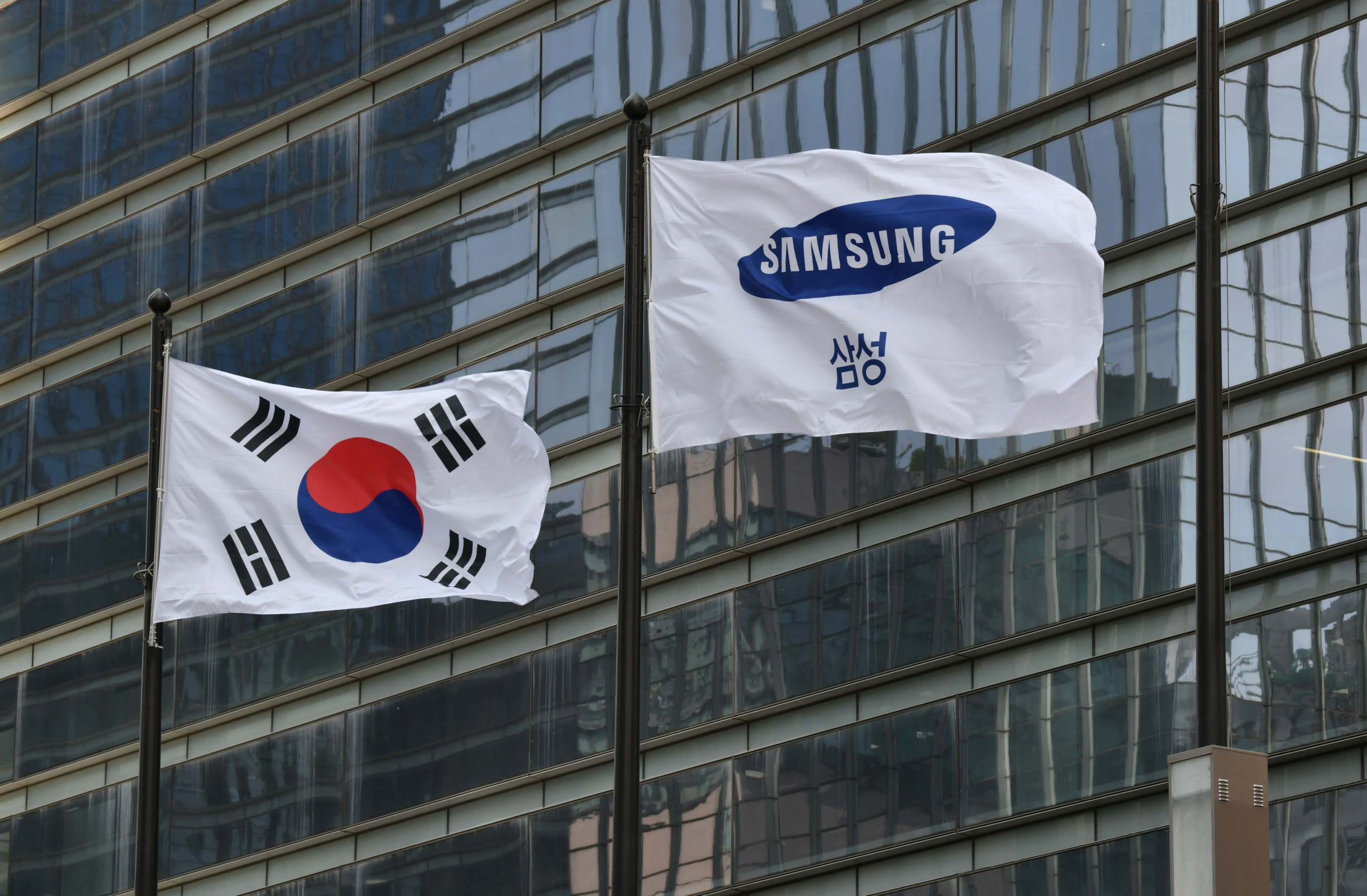Lá cờ Samsung (phải) và quốc kỳ Nam Hàn tung bay bên ngoài tòa nhà Seocho của công ty ở Seoul ngày 06/05/2020. (Ảnh: Jung Yeon-je/AFP/Getty Images)