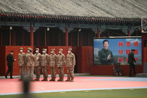 Nhân viên an ninh đứng gác ở lối vào Tử Cấm Thành gần bức ảnh của lãnh đạo Trung Quốc Tập Cận Bình (phải), khi phiên bế mạc của Đại hội Đại biểu Nhân dân Toàn quốc (NPC) diễn ra tại Đại lễ đường Nhân dân gần đó ở Bắc Kinh vào ngày 11/03/2022. (Ảnh: Noel Celis/AFP qua Getty Images)