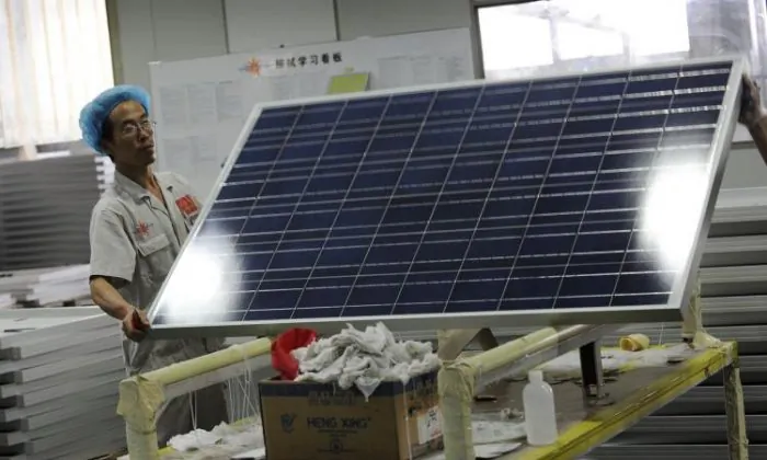 Một công nhân nâng một tấm pin quang năng tại nhà máy Anh lợi Quang năng (Yingli Solar) ở Bảo Định, tỉnh Hà Bắc, Trung Quốc vào ngày 30/09/2010. (Ảnh: Peter Parks/AFP/Getty Images)