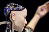 Một robot AI có tên “Alter 3: Offloaded Agency" được chụp trong một cuốn sách quảng cáo để quảng bá cho triển lãm có tên “AI: Hơn cả con người” tại Trung tâm Barbican ở London ngày 15/05/2019. (Ảnh: Ben Stansall/AFP qua Getty Images)