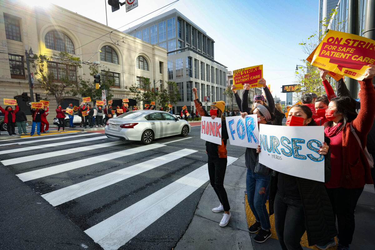 Các y tá và nhân viên chăm sóc sức khỏe của Sutter Health cầm các biểu ngữ khi họ tham gia cuộc đình công kéo dài một ngày bên ngoài Cơ sở Van Ness của Trung tâm Y tế Thái Bình Dương California ở San Francisco, California, vào ngày 18/04/2022. (Ảnh: Justin Sullivan/Getty Images)
