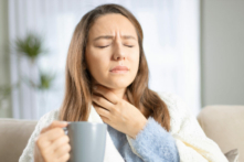Một phụ nữ trẻ đang chạm vào vùng cổ do đau họng vì cảm cúm, cảm lạnh và nhiễm trùng. (Ảnh: Ahmet Misirligul/Shutterstock)