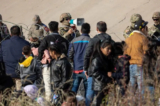 Một binh sĩ thuộc Lực lượng Vệ binh Quốc gia Texas nói chuyện với những người nhập cư tại khu vực có nhiều người vượt biên trái phép dọc theo sông Rio Grande ở thành phố El Paso, Texas, vào ngày 20/12/2022. (Ảnh: John Moore/Getty Images)