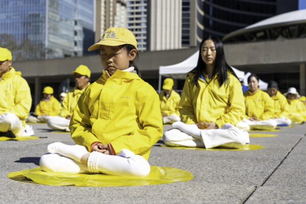 Các học viên Pháp Luân Đại Pháp trình diễn bài thiền định của môn tu luyện này trong một cuộc mít tinh tại Tòa thị chính Toronto hôm 06/05/2023. (Ảnh: Evan Ning/The Epoch Times)