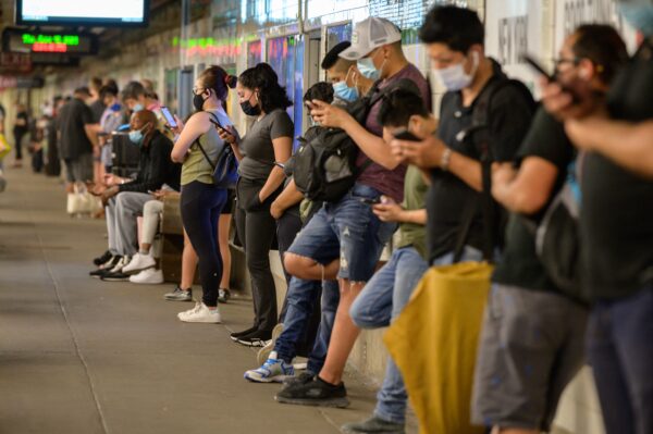 Người đi làm bằng tàu điện ngầm xem điện thoại di động trong lúc chờ tàu ở New York vào ngày 10/06/2021. (Ảnh: Ed Jones/AFP qua Getty Images)