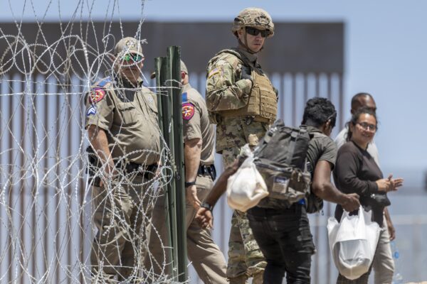 Một binh sĩ Vệ binh Quốc gia Texas đứng nhìn một người nhập cư bất hợp pháp bước vào một khu trại tạm thời ở El Paso, Texas, hôm 11/05/2023. (Ảnh: John Moore/Getty Images)