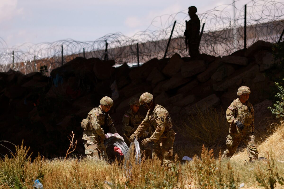 Các thành viên của Lực lượng Vệ binh Quốc gia thuộc Quân đội Texas giăng dây thép gai để ngăn người nhập cư băng qua. Cảnh tượng nhìn từ Ciudad Juarez, Mexico hôm 13/05/2023. (Ảnh: Jose Luis Gonzalez/Reuters)