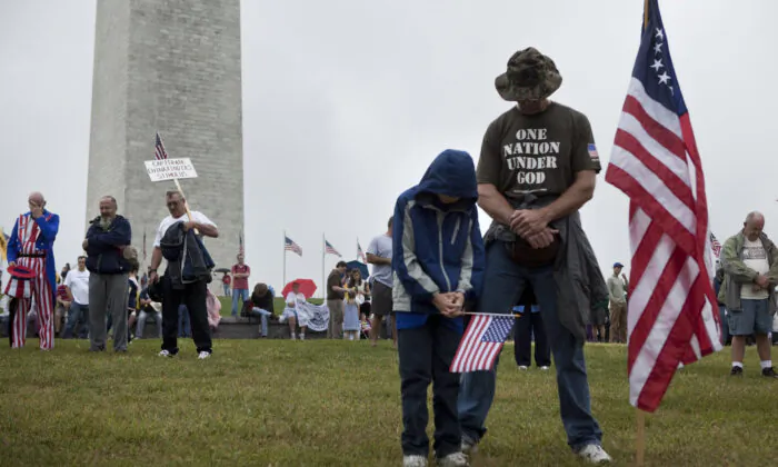 Người dân cúi đầu cầu nguyện trong một cuộc biểu tình ở National Mall gần Đài tưởng niệm Washington vào ngày 12/09/2010 tại Thủ đô Hoa Thịnh Đốn. (Ảnh: Brendan Smialowski/Getty Images)