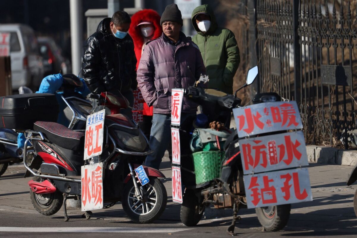 Những người lao động nhập cư đứng gần các tấm biển cho thấy những kỹ năng của họ khi họ chờ được thuê bên một con phố ở Thẩm Dương, tỉnh Liêu Ninh, phía đông bắc Trung Quốc hôm 06/02/2023. (Ảnh: STR/AFP qua Getty Images)