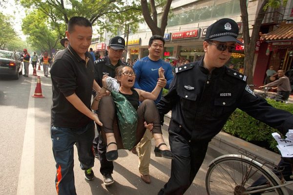 Một người khiếu kiện bị công an đưa đi bên ngoài bệnh viện nơi nhà hoạt động nhân quyền Trần Quang Thành đang điều trị tại Bắc Kinh vào ngày 05/05. Người phụ nữ này bày tỏ sự không hài lòng với cách đối xử của chính quyền Trung Quốc dành cho những người khiếu kiện, đã yêu cầu được gặp ông Trần. (Ảnh: Ed Jones/AFP/GettyImages)