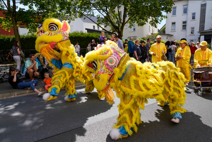 Công chúng chào đón đoàn diễn hành của các học viên Pháp Luân Công tại lễ hội văn hóa Carnival ở Bielefeld, Đức