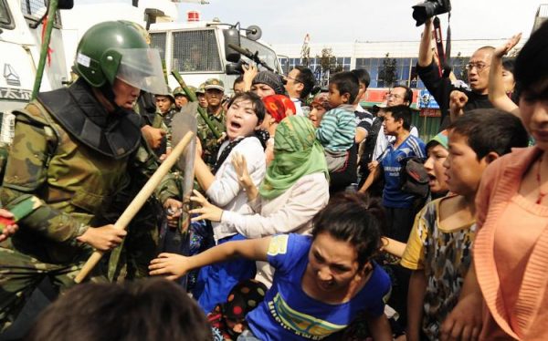 Công an chống bạo động Trung Quốc chạm trán với các phụ nữ người dân tộc Duy Ngô Nhĩ đang phản đối việc tịch thu đất đai, chấm dứt hợp đồng cho thuê, và giam giữ những người đàn ông trong dân làng ở Ô Lỗ Mộc Tề (Urumqi) thuộc tỉnh Tân Cương viễn tây Trung Quốc, vào ngày 07/07/2009. (Ảnh: Peter Parks/AFP/Getty Images)