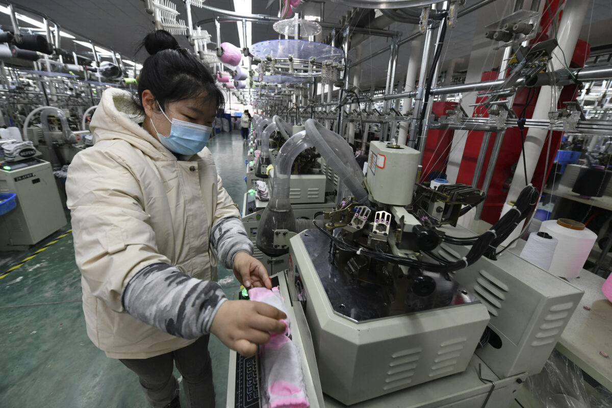 Một công nhân vận hành máy đan vớ trong một nhà máy ở huyện Phù Nam, tỉnh An Huy, miền trung Trung Quốc hôm 01/03/2022. (Ảnh: Chinatopix qua AP)