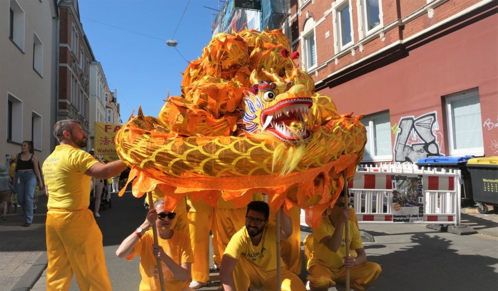 Công chúng chào đón đoàn diễn hành của các học viên Pháp Luân Công tại lễ hội văn hóa Carnival ở Bielefeld, Đức