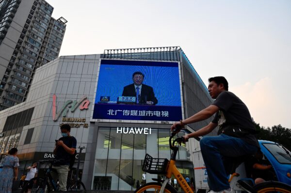 Một màn hình chiếu tin thời sự trong đó lãnh đạo ĐCSTQ Tập Cận Bình đang đọc diễn văn trong một hội nghị thượng đỉnh các đảng chính trị thế giới, khi mọi người đi bộ bên ngoài một trung tâm mua sắm ở Bắc Kinh vào ngày 07/07/2021. (Ảnh: Jade Gao/AFP qua Getty Images)