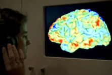 Một người phụ nữ quan sát một phim chụp cộng hưởng từ chức năng (fMRI). Phim chụp cho thấy tác động của tác phẩm Rite of Spring của Stravinsky và 3rd Critique của Kant đối với bộ não trong cuộc triển lãm lớn mới đây của Wellcome Collection "Brains: mind of matter” (Tạm dịch: Bộ não: tâm trí của vật chất) được tổ chức tại London, 27/03/2012. (Ảnh: Miguel Medina/AFP/Getty Images)