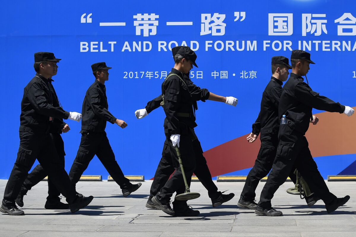 Các nhân viên bảo vệ đi ngang qua một bảng quảng cáo cho Diễn đàn Hợp tác Quốc tế Vành đai và Con đường tại địa điểm diễn đàn ở Bắc Kinh vào ngày 13/05/2017. (Ảnh: Wang Zhao/AFP qua Getty Images)