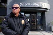 Một nhân viên bảo vệ tại ngân hàng đã sụp đổ Silicon Valley Bank theo dõi hàng người bên ngoài văn phòng ở Santa Clara, California, hôm 13/03/2023. (Ảnh: Justin Sullivan/Getty Images)