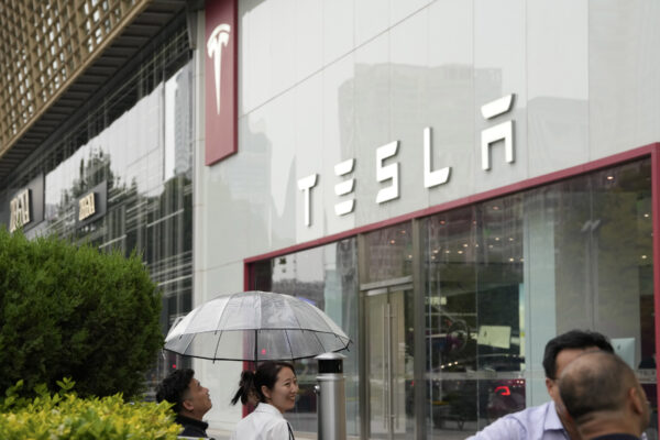 Nhân viên trò chuyện dưới một chiếc ô bên ngoài phòng trưng bày Tesla ở Bắc Kinh, Trung Quốc, hôm 30/05/2023. (Ảnh: AP Photo/Ng Han Guan)