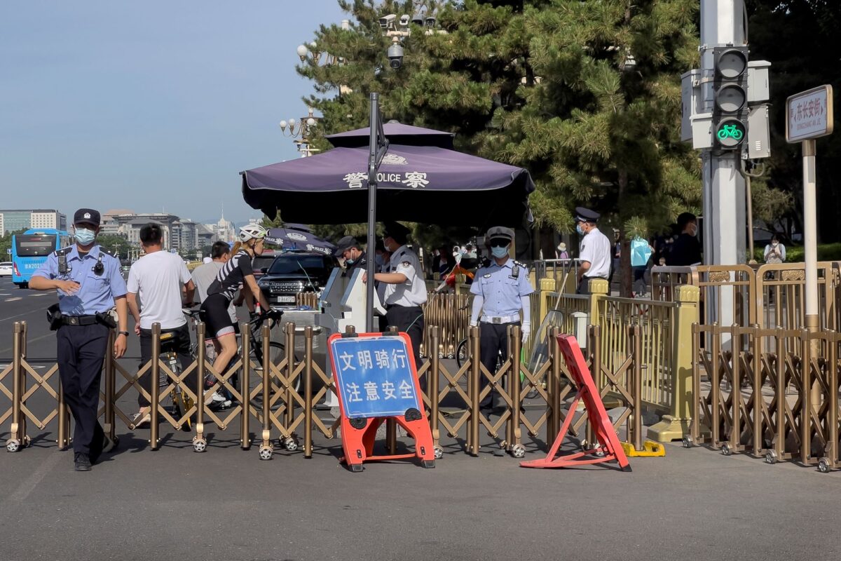 Một nhân viên cảnh sát (Trái) ra hiệu cho một ký giả dừng lại khi những người đi xe đạp được lệnh dừng lại để kiểm tra giấy tờ tùy thân tại một trạm kiểm soát dọc một con phố gần Quảng trường Thiên An Môn ở Bắc Kinh hôm 04/06/2023, trong dịp kỷ niệm 34 năm vụ thảm sát đẫm máu năm 1989 của ĐCSTQ đối với những người biểu tình đòi dân chủ. (Ảnh: Andy Wong/AP Photo)