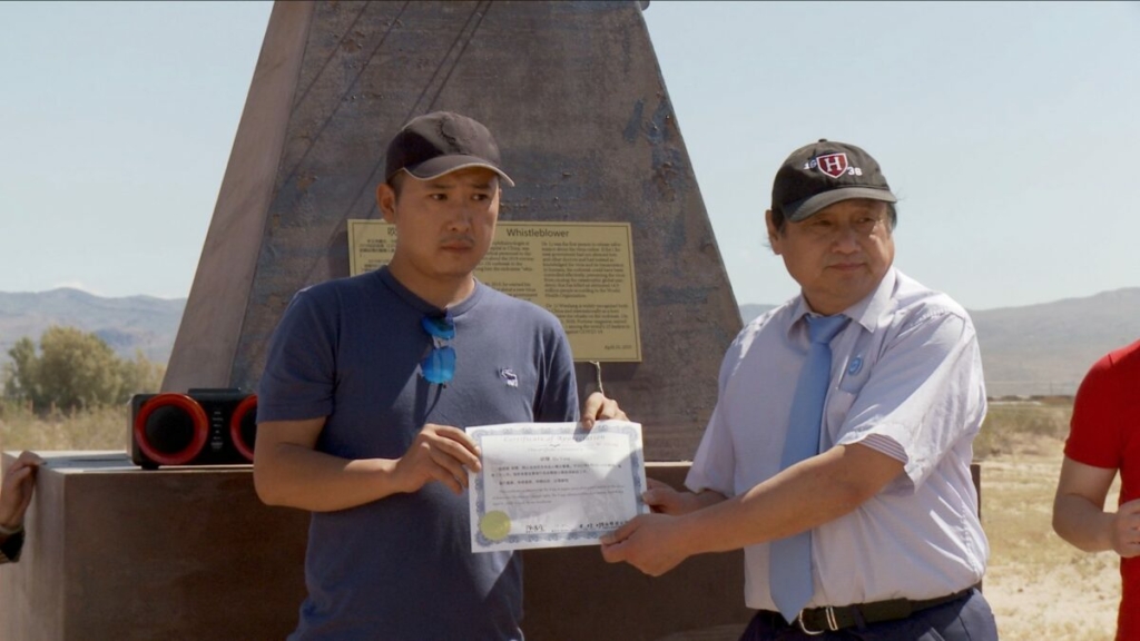 Ông Hồ Dương (Hu Yang) nhận được giấy chứng nhận từ Đảng Dân Chủ Trung Quốc để ghi nhận công việc tình nguyện của ông, tại Công viên Điêu khắc Liberty, hôm 23/04/2023. (Ảnh: Đăng dưới sự cho phép của ông Hu Yang)