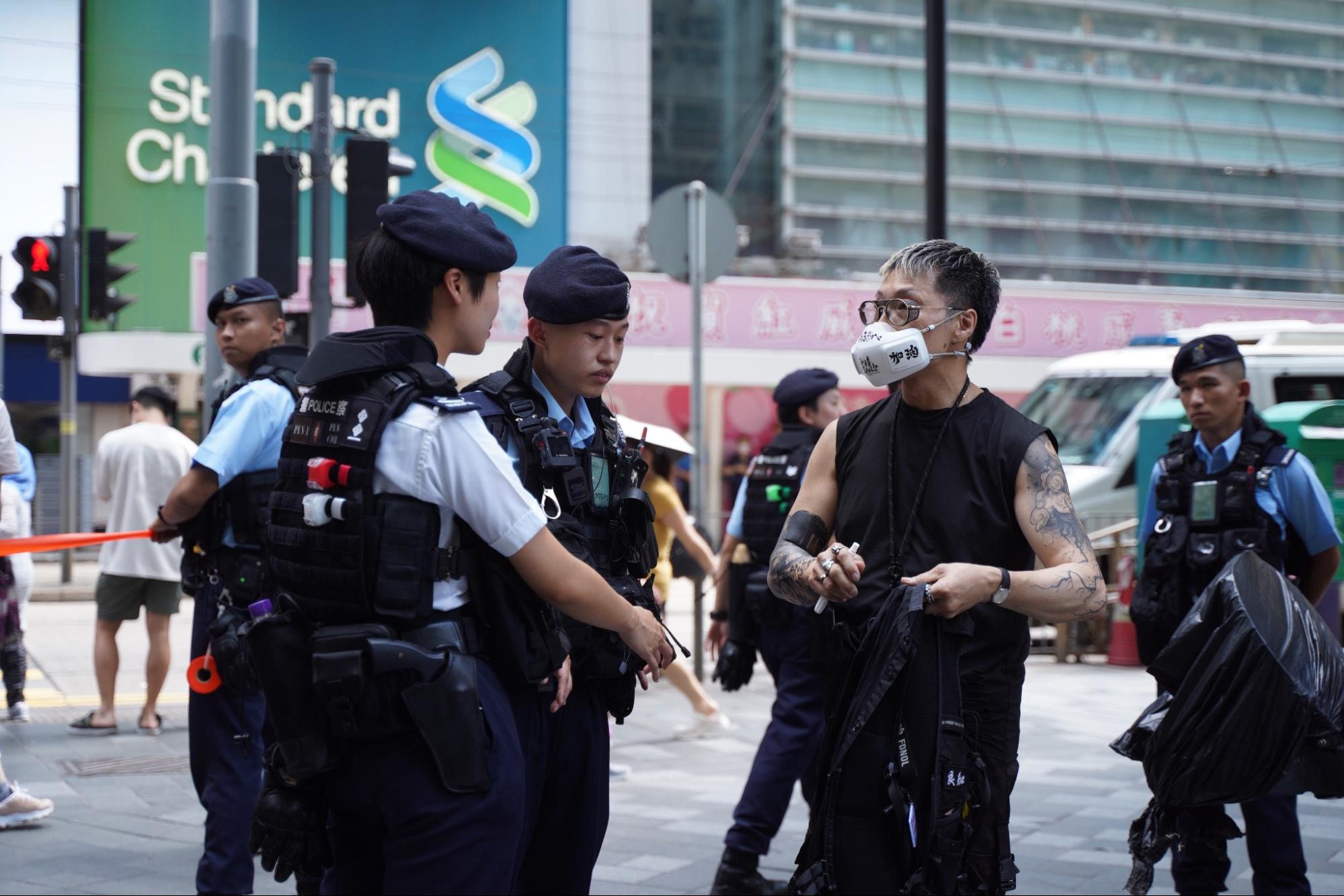 Một người đàn ông mặc một áo phông đen và đeo một chiếc khẩu trang có dòng chữ “Hong Kong Add Oil” đã bị cảnh sát chặn lại và khám xét. (Ảnh: Sung Pi-lung/The Epoch Times)