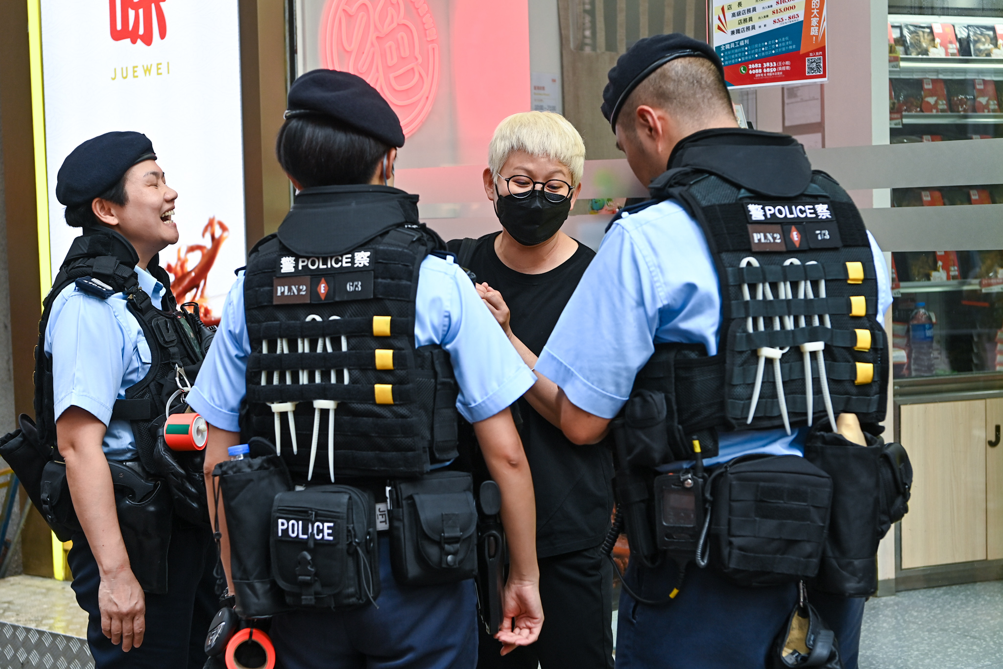 Cô Trương, một phụ nữ đeo một khẩu trang và mặc áo phông màu đen, đã bị cảnh sát chặn lại và khám xét. (Ảnh: Benson Lau/The Epoch Times)