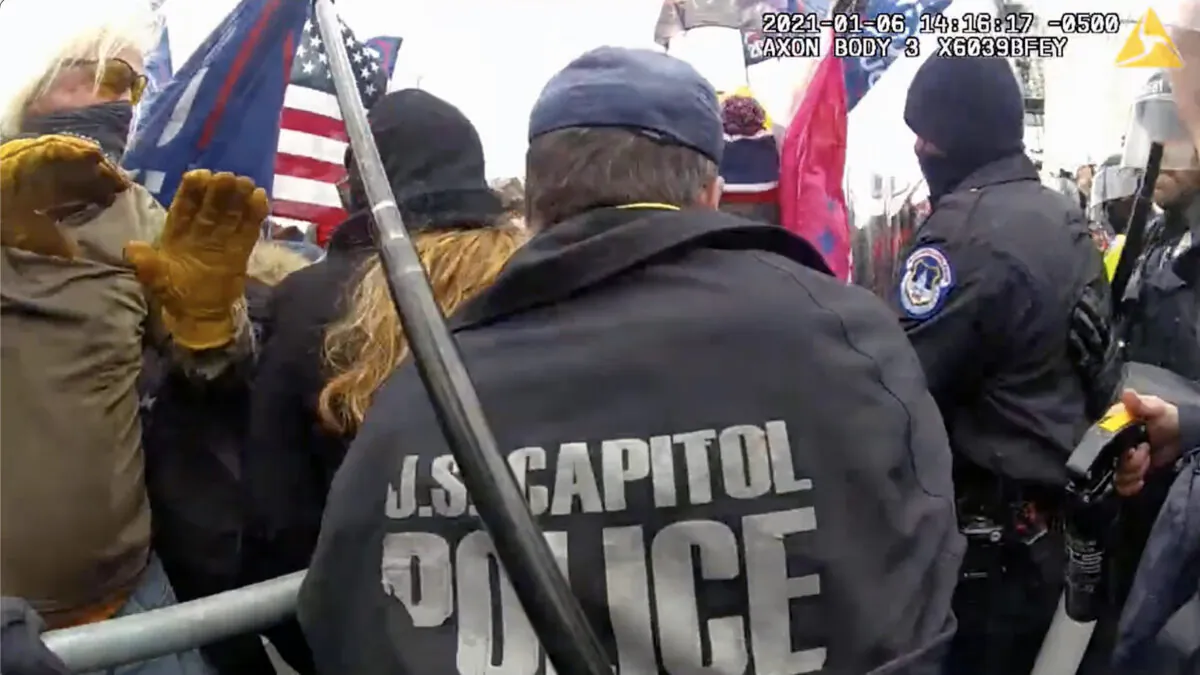 Hai cảnh sát Điện Capitol Hoa Kỳ không đội nón bảo hiểm tại hàng rào cảnh sát ở mặt tiền phía tây của Điện Capitol vào ngày 06/01/2021. (Ảnh: Sở Cảnh sát Thủ đô/Ảnh chụp màn hình qua The Epoch Times)