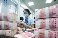 Một nhân viên ngân hàng đếm các tờ mệnh giá 100 nhân dân tệ tại quầy ngân hàng ở Nam Thông, phía đông tỉnh Giang Tô của Trung Quốc hôm 13/06/2023. (Ảnh: STR/AFP qua Getty Images)