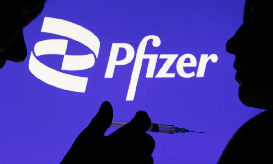 Hình ảnh một người tạo dáng với ống chích trước logo Pfizer Inc. vào ngày 11/12/2021. (Ảnh: Dado Ruvic/Reuters)