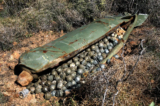 Một trái bom chùm “mẹ” chứa hơn 600 trái bom con, được chiến đấu cơ của Israel thả xuống trong cuộc chiến tranh Hezbollah-Israel kéo dài 34 ngày, nằm trên một cánh đồng ở ngôi làng phía nam Ouazaiyeh, Lebanon, vào ngày 09/11/2006. (Ảnh: Mohammed Zaatari/AP Photo)
