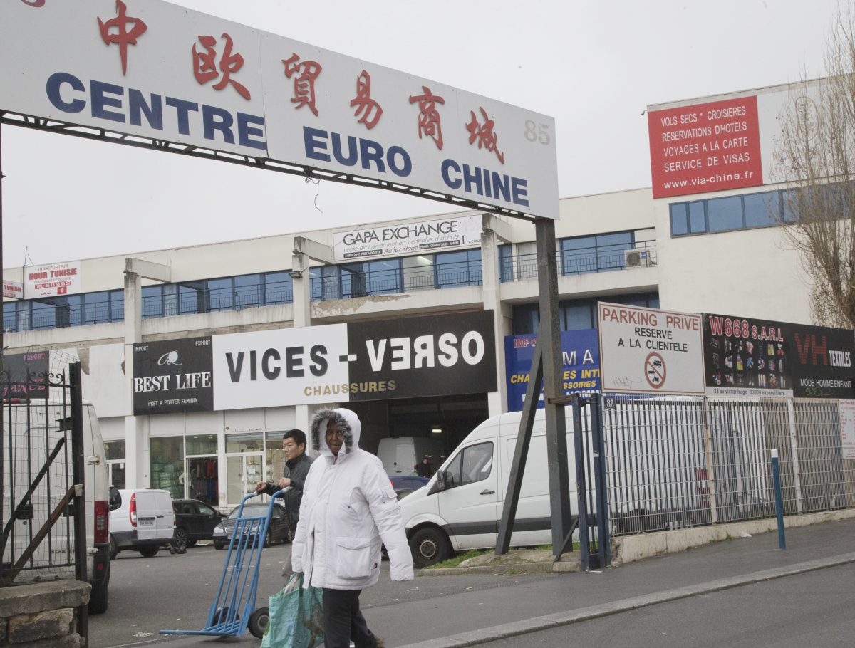 Khách bộ hành trong khu bán buôn quần áo Trung Quốc ở Aubervilliers, phía bắc Paris vào ngày 24/02/2016. Các thương nhân Trung Quốc bị buộc tội rửa tiền cho những kẻ buôn bán ma túy ở Bắc Phi. Tấm biển hiệu bằng Hoa ngữ ghi là “Thành phố Thương mại và Mậu dịch Trung Quốc Châu Âu.” (Ảnh: AP Photo/Jacques Brinon)