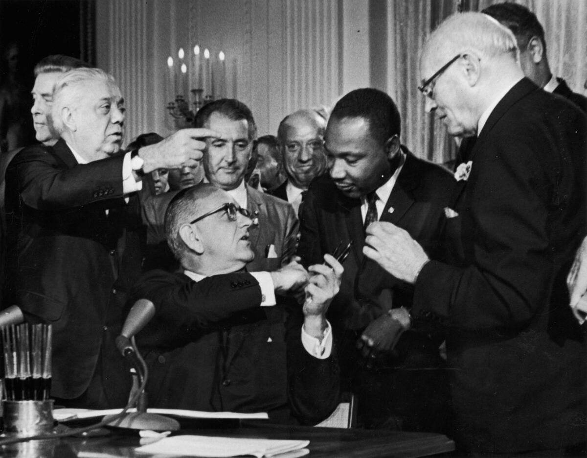 Tổng thống Lyndon B. Johnson bắt tay Tiến sĩ Martin Luther King Jr. tại lễ ký kết Đạo luật Dân quyền trước sự chứng kiến của các quan chức ​​tại Hoa Thịnh Đốn hôm 02/07/1964. (Ảnh: Hulton Archive/Getty Images)