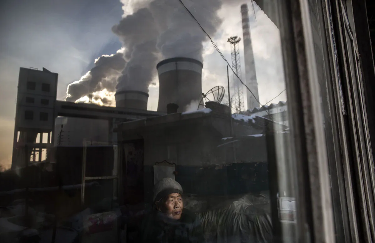 Một cư dân Trung Quốc nhìn ra cửa sổ ngôi nhà của mình bên cạnh một nhà máy nhiệt điện than ở tỉnh Sơn Tây, Trung Quốc, vào ngày 26/11/2015. (Ảnh: Kevin Frayer/Getty Images)