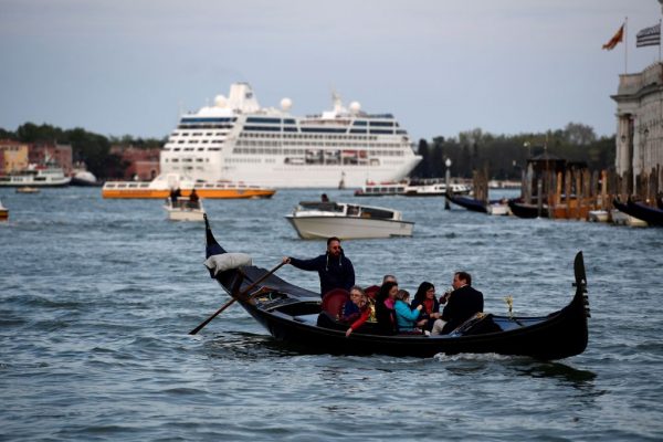 Một chiếc tàu du lịch và một chiếc thuyền gondola chở khách du lịch di chuyển ở lối vào Canale Grande (Kênh Lớn) ở thành phố Venice, nước Ý, vào ngày 07/04/2017. (Ảnh: Miguel Medina/AFP/Getty Images)