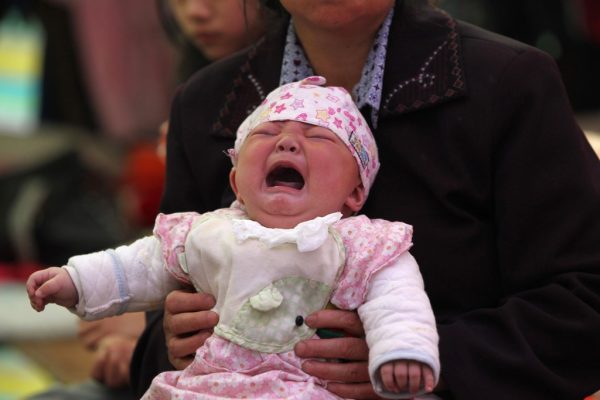 Một em bé khóc trong vòng tay của mẹ ở thị trấn Nhã An, phía tây nam tỉnh Tứ Xuyên, Trung Quốc, vào ngày 23/04/2013. (Ảnh: AFP/Getty Images)
