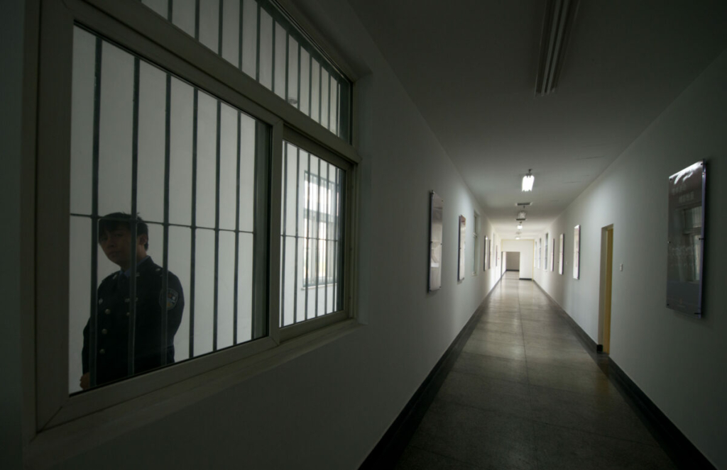 Một lính canh nhìn qua cửa sổ của hành lang bên trong Trung tâm giam giữ số 1 trong chuyến tham quan do chính quyền hướng dẫn ở Bắc Kinh vào ngày 25/10/2012. (Ảnh: Ed Jones/AFP qua Getty Images)