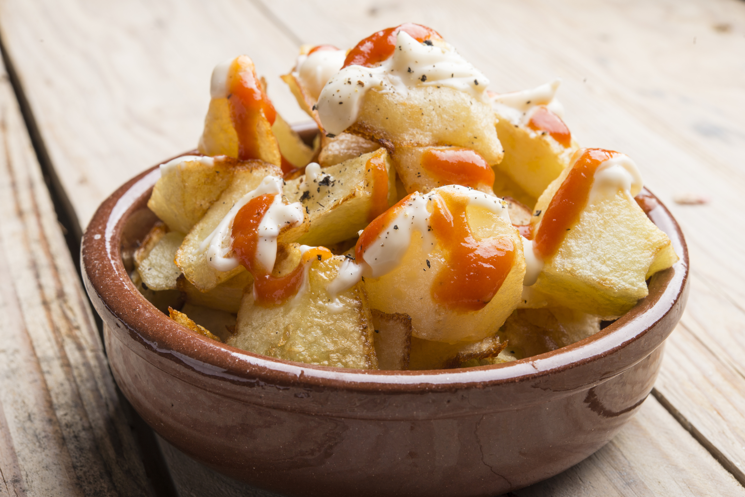 Khoai tây cay là những miếng khoai tây chiên phủ sốt cà chua cay đặc biệt và sốt tỏi trắng. (Ảnh: Shutterstock)