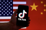 Logo của ứng dụng mạng xã hội TikTok hiển thị trên màn hình iPhone, trước nền quốc kỳ của Hoa Kỳ và Trung Quốc tại Hoa Thịnh Đốn hôm 16/03/2023. (Ảnh: Olivier Douliery/AFP qua Getty Images)