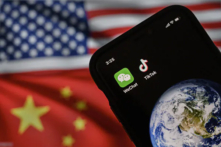 Trong ảnh minh họa này, có thể thấy một chiếc điện thoại di động đang hiển thị logo của hai ứng dụng Trung Quốc là WeChat và TikTok trước màn hình hiển thị quốc kỳ của Hoa Kỳ và Trung Quốc trên một trang mạng internet. (Ảnh: Kevin Frayer/Getty Images)