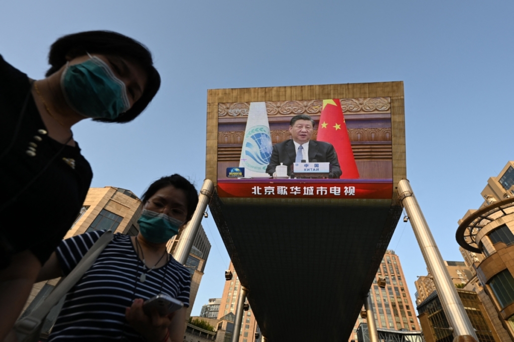 Hai người phụ nữ chờ đợi bên dưới một màn hình khổng lồ chiếu tin tức thời sự về việc Chủ tịch Trung Quốc Tập Cận Bình có bài diễn văn trực tuyến tại cuộc họp của Tổ chức Hợp tác Thượng Hải, được tổ chức ở Ấn Độ, tại một trung tâm mua sắm ở Bắc Kinh hôm 04/07/2023. (Ảnh: Greg Baker/AFP qua Getty Images)