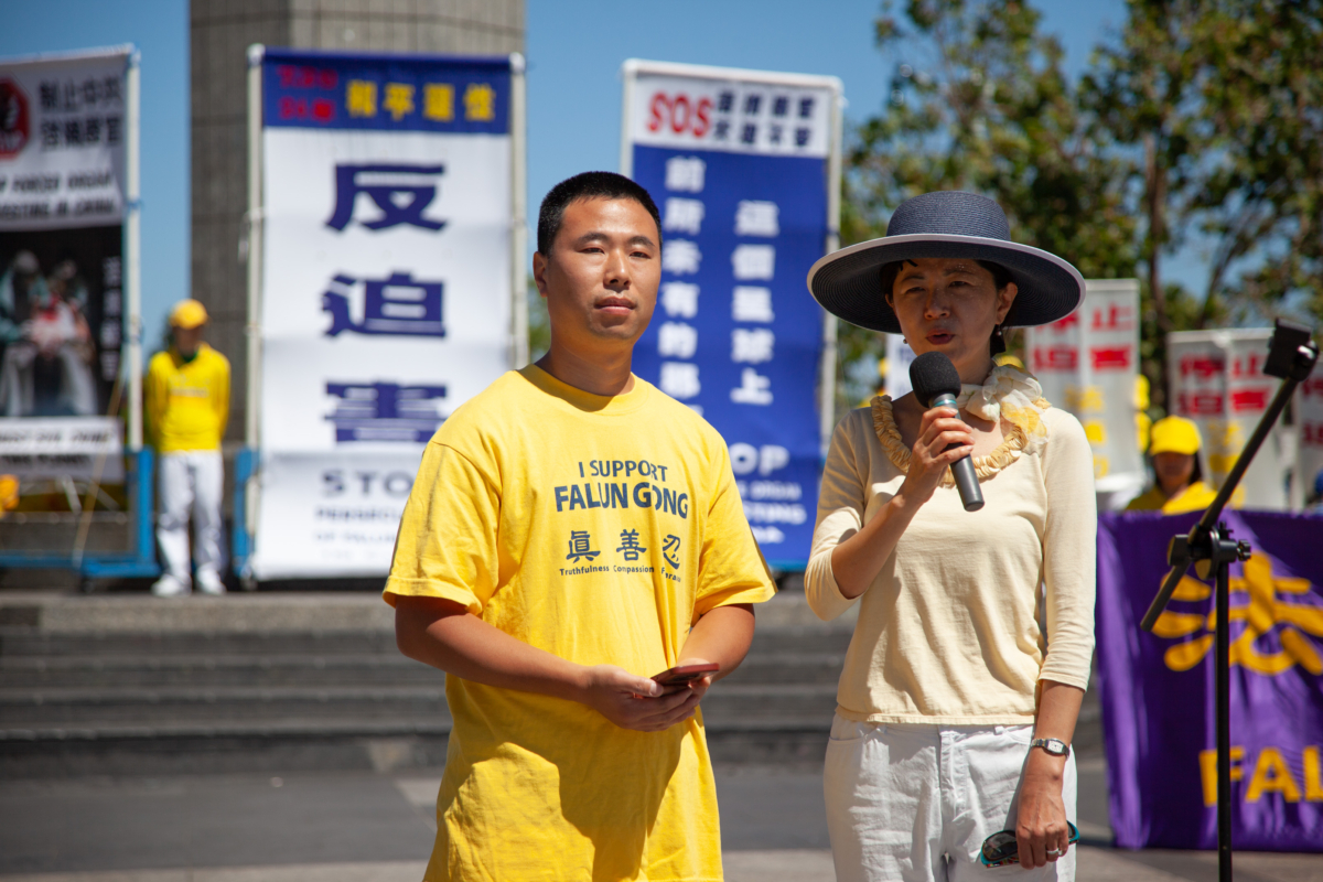 Anh Vương Long Tiêu (trái) đang đứng nhìn trong khi một thông dịch viên kể câu chuyện của anh về việc đào thoát khỏi cuộc bức hại ở Trung Quốc tại một cuộc mít tinh ở San Francisco, hôm 15/07/2023. (Ảnh: Lear Zhou/The Epoch Times)