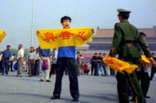 Một viên công an Trung Quốc tiếp cận một học viên Pháp Luân Công tại Quảng trường Thiên An Môn ở Bắc Kinh khi người này cầm một biểu ngữ Hán tự “chân, thiện, và   nhẫn,” các nguyên lý cốt lõi của Pháp Luân Công. (Ảnh: Được đăng dưới sự cho phép của Minghui.org)