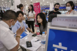Một nam và một nữ thanh niên nói chuyện với nhà tuyển dụng khi họ tìm việc làm tại một hội chợ việc làm hôm 09/06/2023 ở Bắc Kinh, Trung Quốc. (Ảnh: Kevin Frayer/Getty Images)