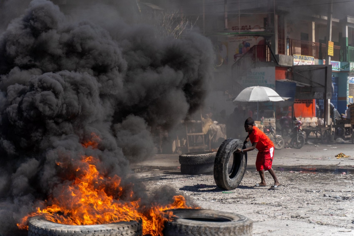 Một người biểu tình đang đưa thêm một vỏ xe vào một hàng chướng ngại vật đang cháy trong một cuộc biểu tình của cảnh sát để phản đối vụ sát hại sáu viên cảnh sát gần đây của các băng đảng có vũ trang s ở Port-au-Prince, Haiti, hôm 26/01/2023. (Ảnh: Richard Pierrin/AFP qua Getty Images)
