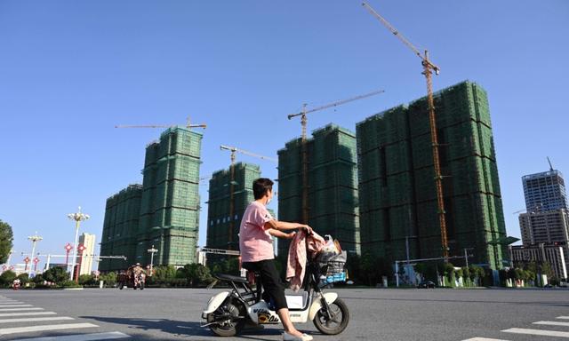 Một người phụ nữ đi xe máy ngang qua công trường xây dựng khu nhà ở của Tập đoàn  Hằng Đại (Evergrande) ở Trú Mã Điếm, tỉnh Hà Nam, miền trung Trung Quốc hôm 14/09/2021. (Ảnh: Jade Gao/AFP qua Getty Images)