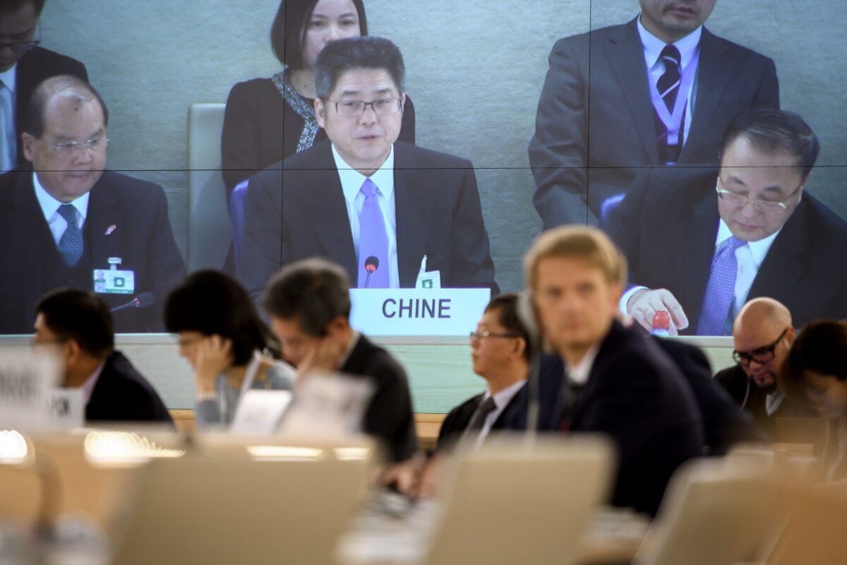 Thứ trưởng Bộ Ngoại giao Trung Quốc Lạc Ngọc Thành (giữa) được nhìn thấy trên một màn hình TV lớn đang đọc diễn văn trước Hội đồng Nhân quyền Liên Hiệp Quốc (LHQ) tại Geneva vào ngày 06/11/2018. (Ảnh: Fabrice Coffrini/AFP qua Getty Images)