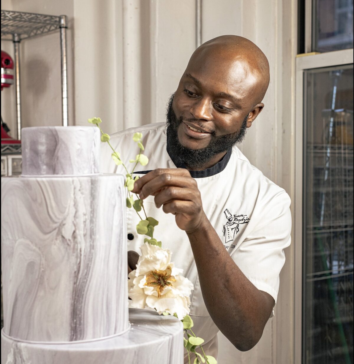 Đầu bếp bánh ngọt Ebow Dadzie trang trí một chiếc bánh bằng những bông hoa thủ công làm từ đường tại xưởng bánh của anh ở Manhattan. (Ảnh: Tatsiana Moon cho tạp chí American Essence)