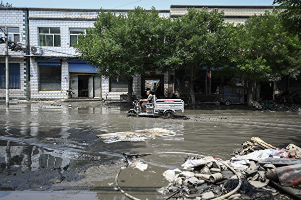 Hôm 09/08/2023, một người dân địa phương lái xe điện ba bánh dọc theo con đường ngập nước ở thành phố Trác Châu, tỉnh Hà Bắc, Trung Quốc. (Ảnh: Jade Gao/AFP)
